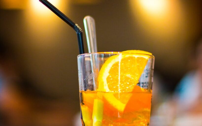 macro photography of clear drinking glass with lemon fruit and black straw